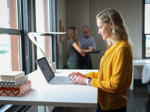 Kvinne arbeider på bærbar PC ved et bord i et lyst kontor